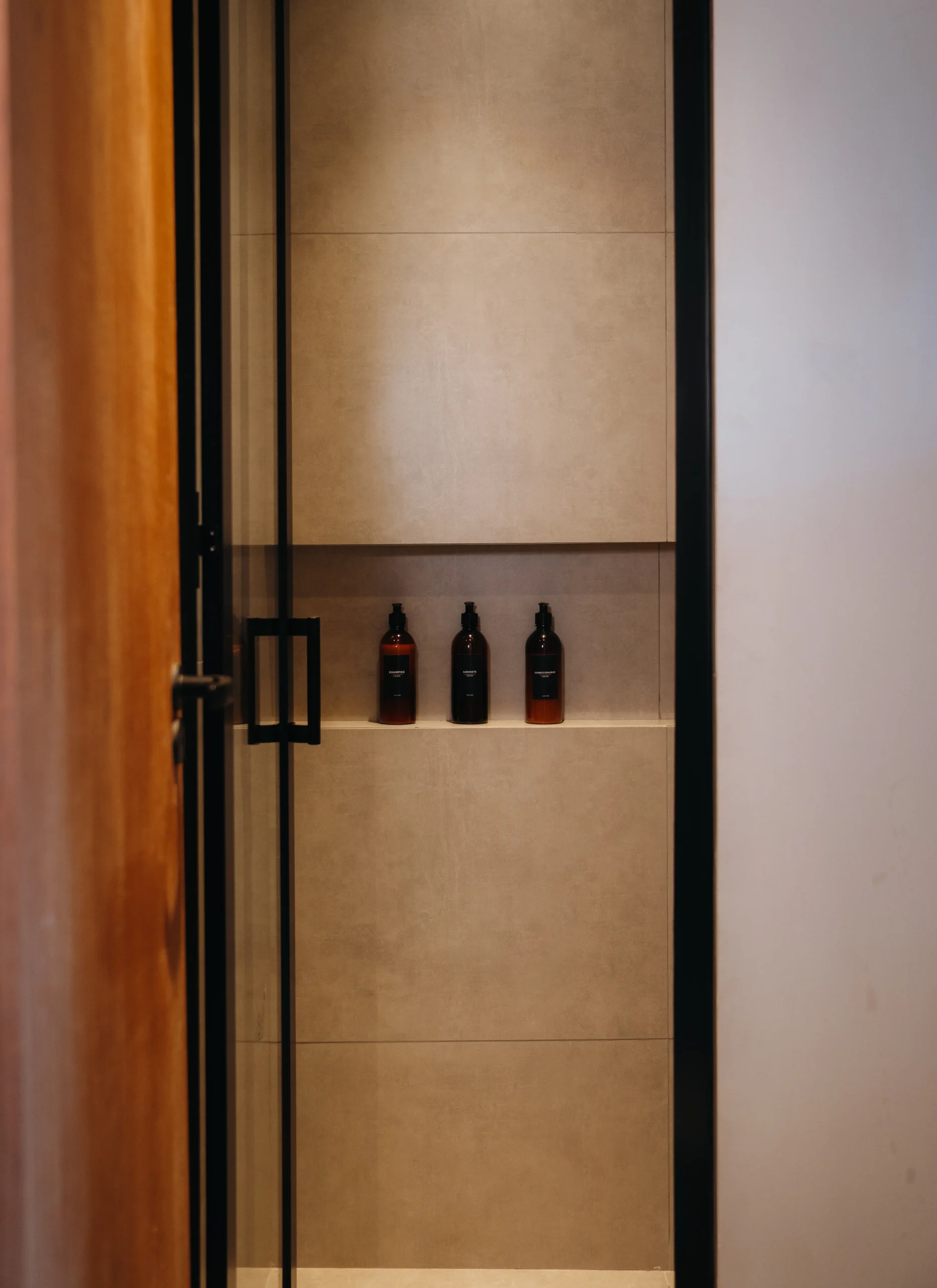 Entrada do banheiro com porta aberta, revelando decoração clean e itens de higiene na Sabai Pousada Boutique Título: Banheiro elegante e funcional